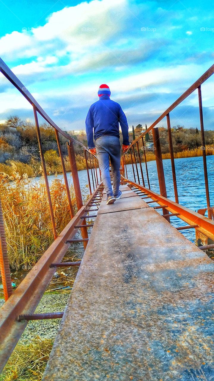 A man from behind on an iron bridge