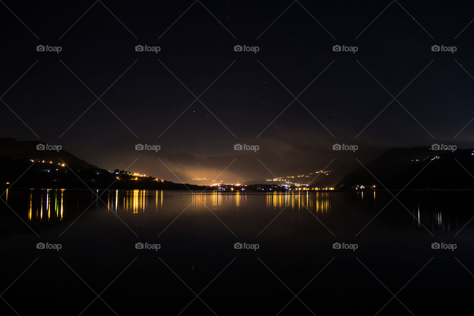 Picture of lights of a town reflecting on a lake.