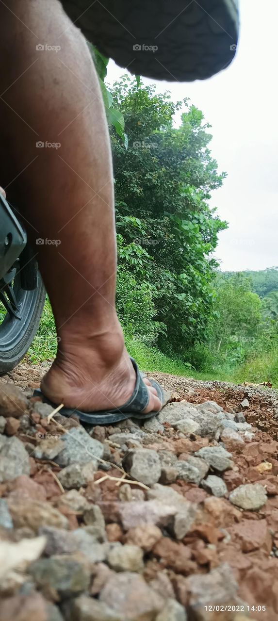 black smooth legs.  with black rubber flip flops with a natural background