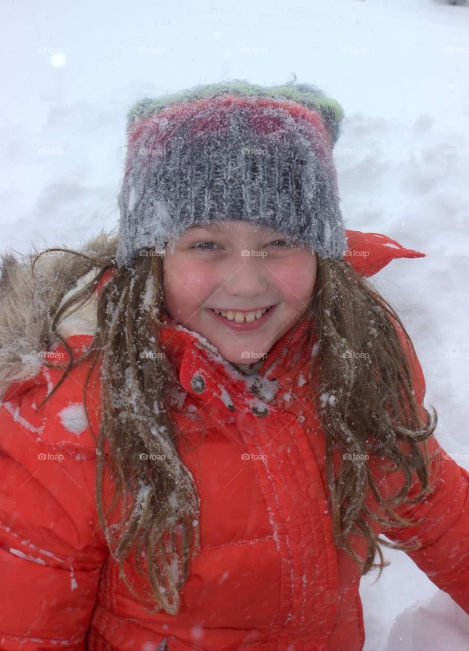 Pretty young girl happily covered in freshly fallen snow. 