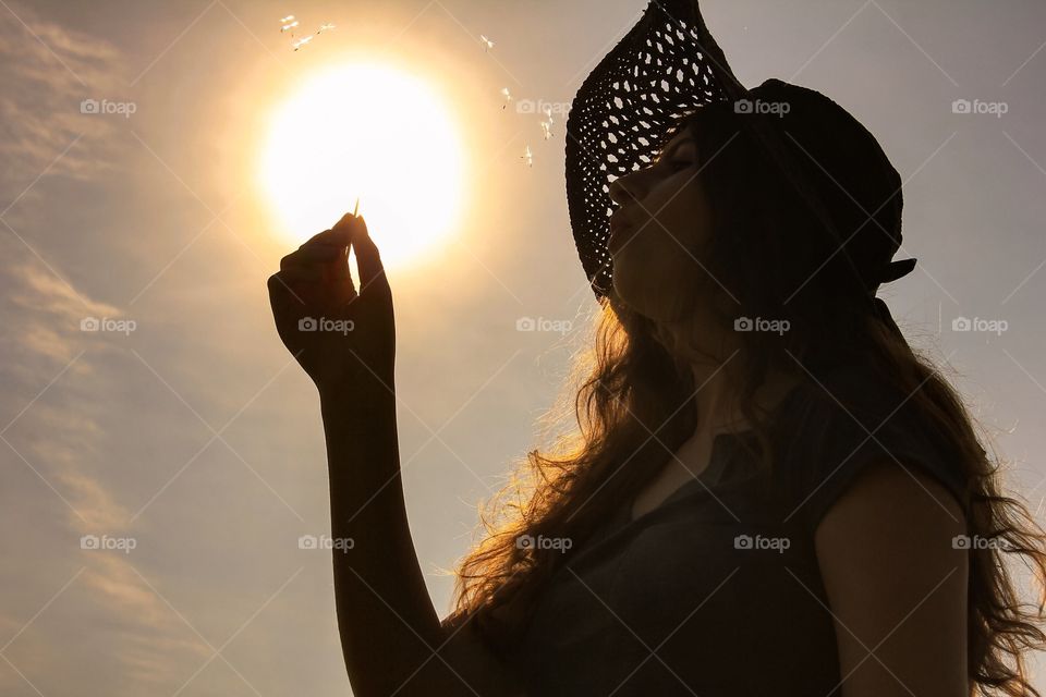 Woman holding toothpick in front of sunlight