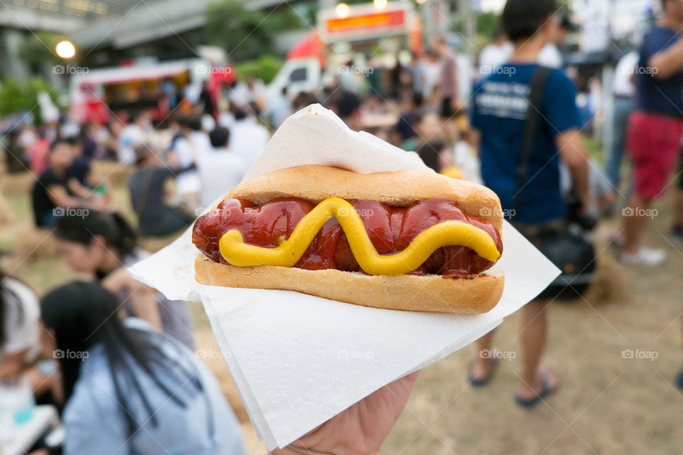Hot dog with sauce. Hot dog in the festival full of people