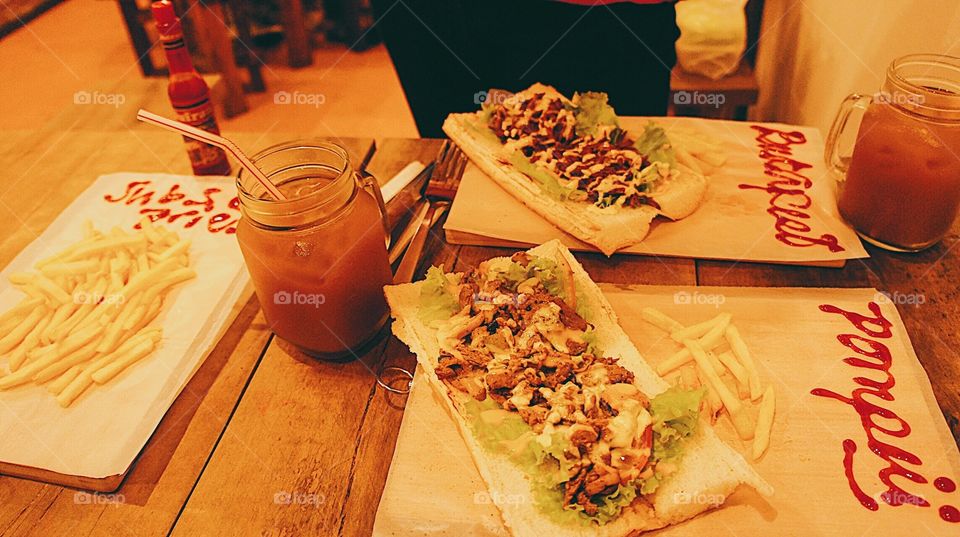 Philly cheesesteak sandwiches with french fries.