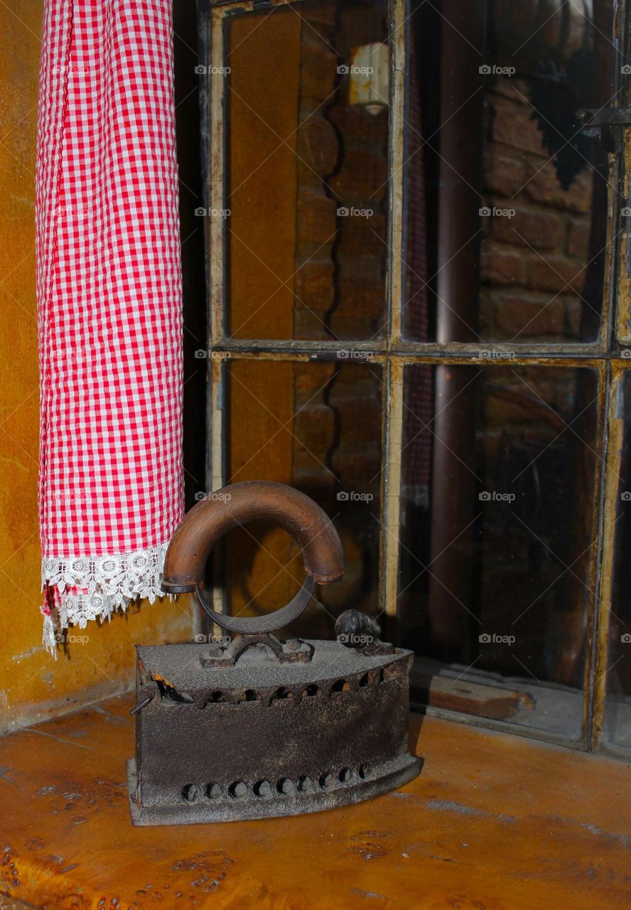 An old metal iron with a wooden handle. This iron did not need electricity, only embers from the wood stove