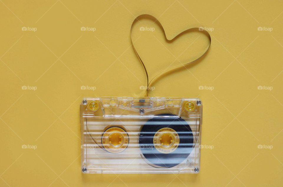 Retro cassette tape on yellow background, love, heart shape