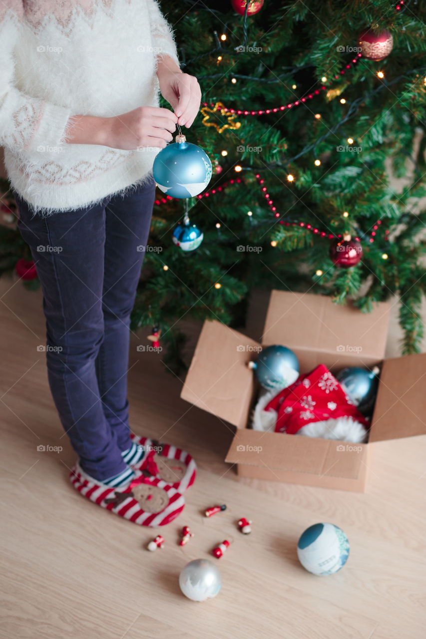 Young girl decorating Christmas tree at home