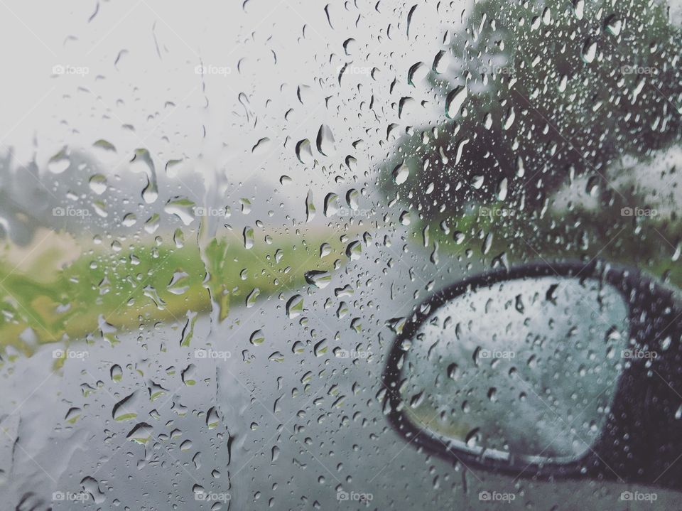 Road seen through wet car windshield during rainy season