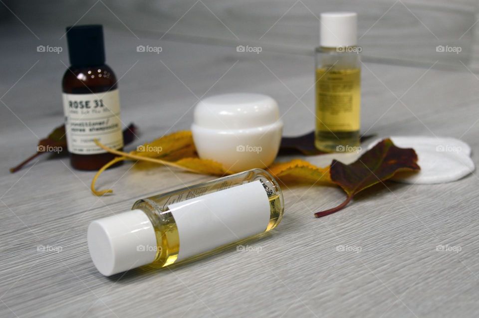 Jars with cream, shampoo and cosmetics on a background with autumn leaves