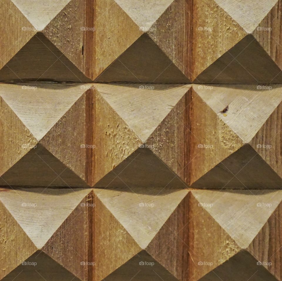 Carved piece of wood into pyramid like shapes ... contrasting rough and smooth texture .. 