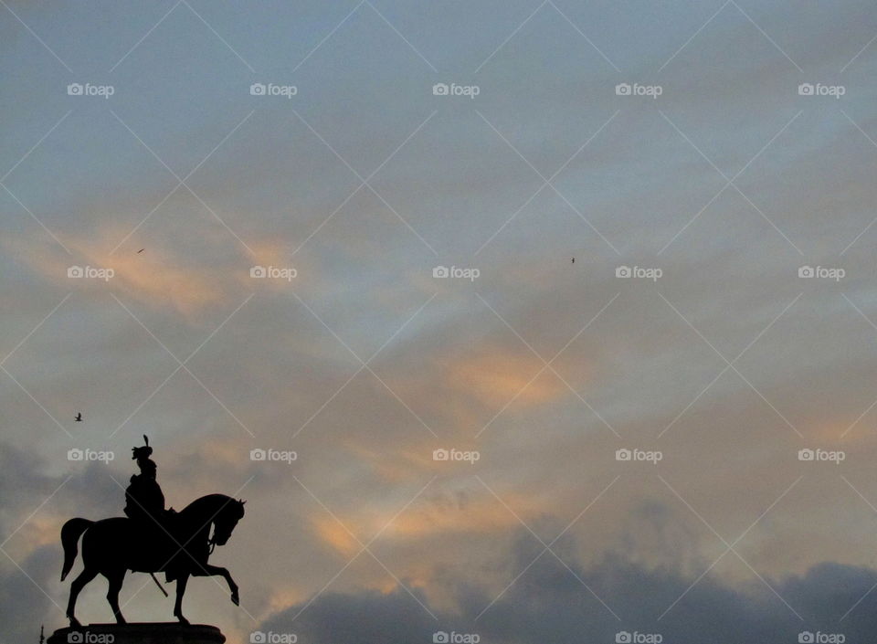 silhouette of knight statue above the city