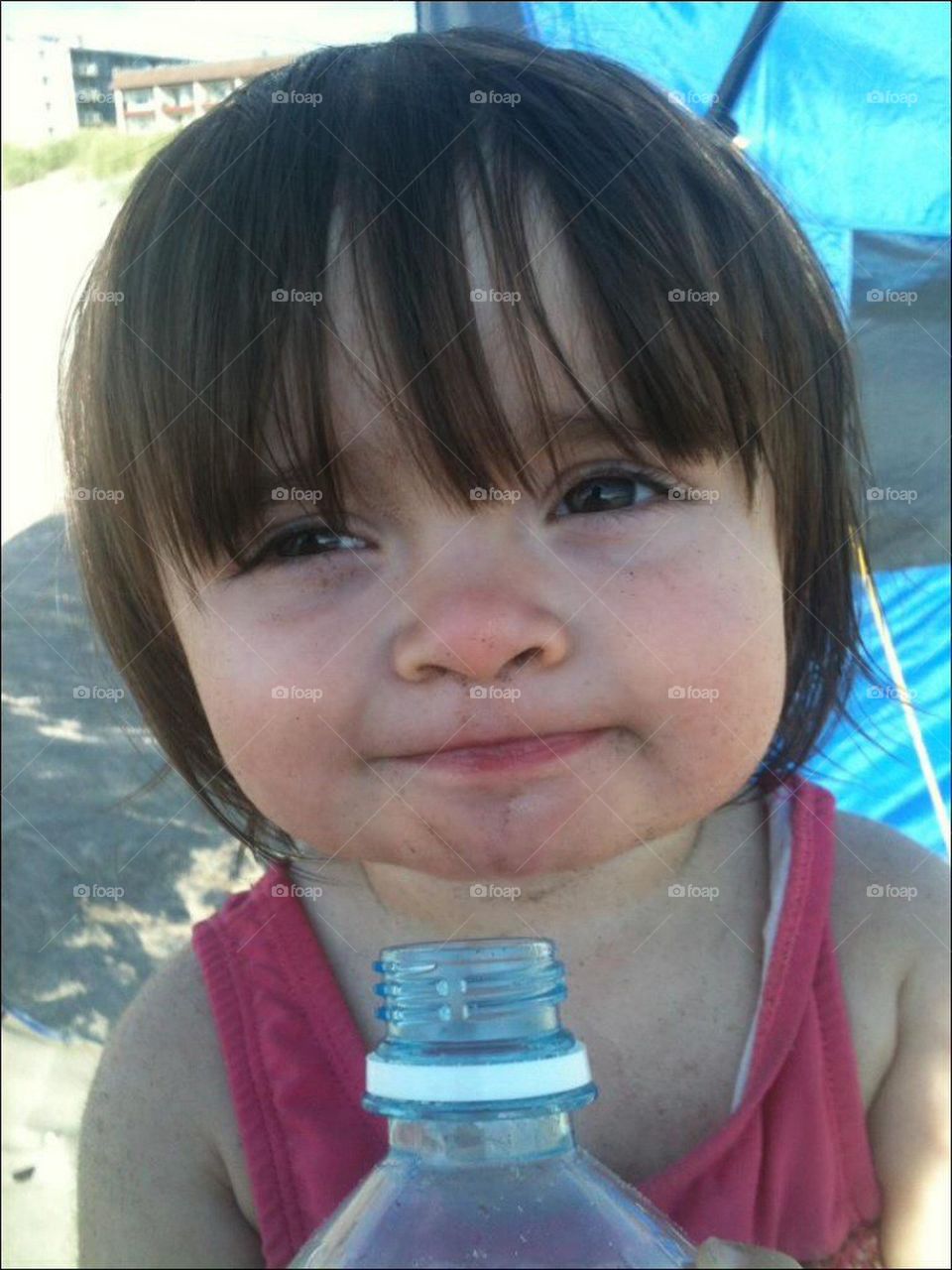 Girl in sand drinking water