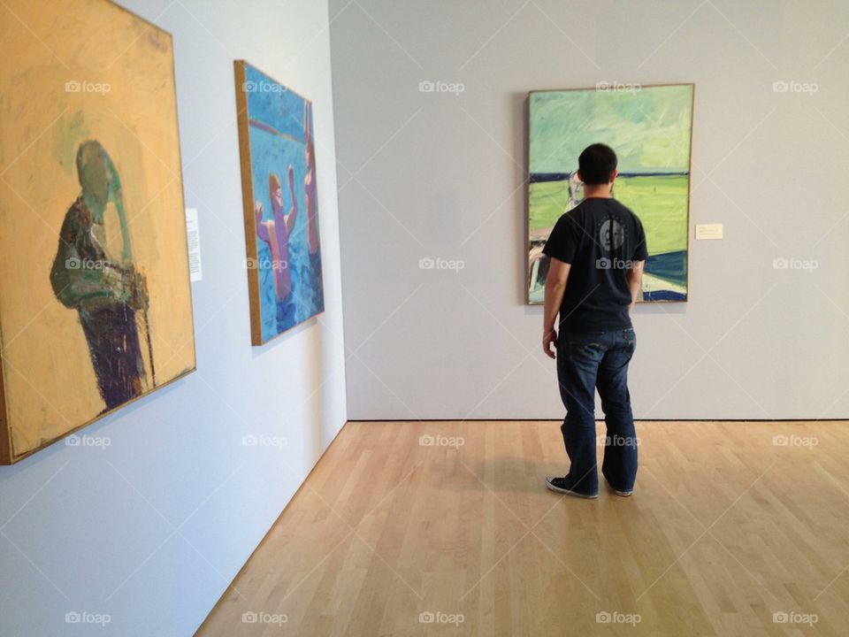 Man looks at paintings in gallery