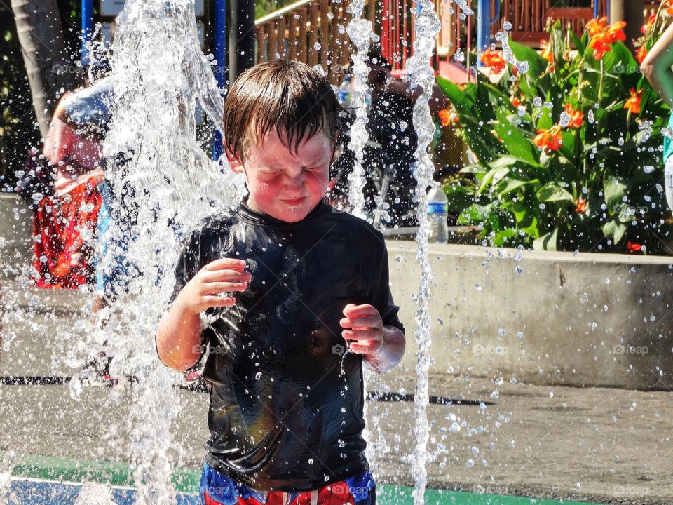 Boy Playing In Water Fountain