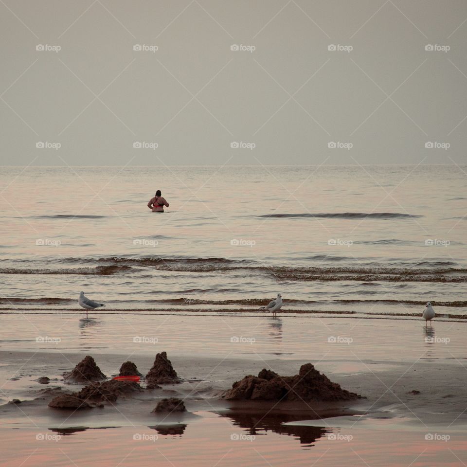 Sunset seascape with a woman    swimming in cold september water