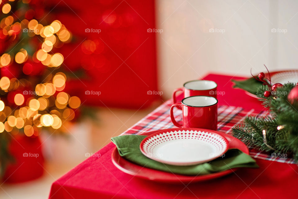 Festive winter cozy kitchen interior with garlands, decorations and gifts.  Christmas dinner at the decorated table.