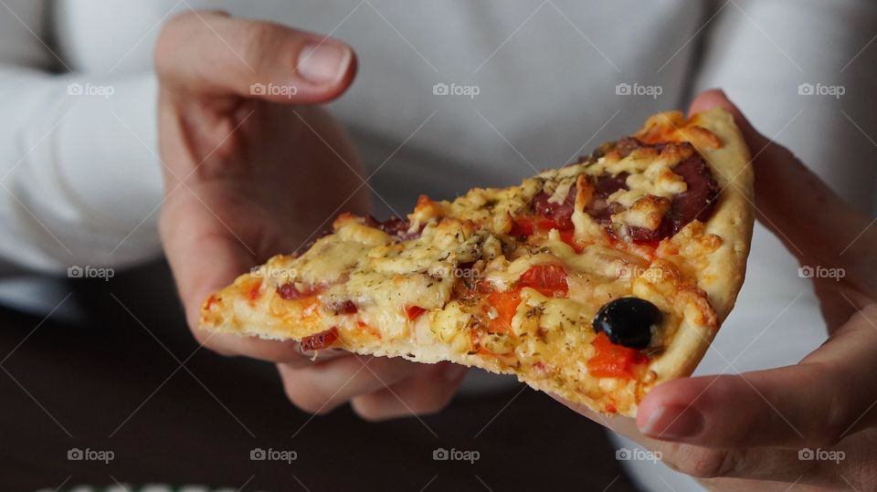 Close-up of woman's hand holding slice of pizza