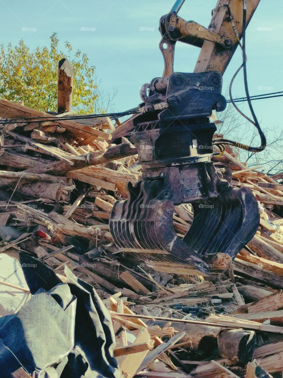 The excavator bucket removes wood planks