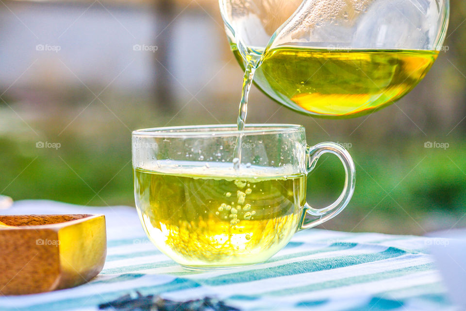 Green tea being poured from teapot into cup