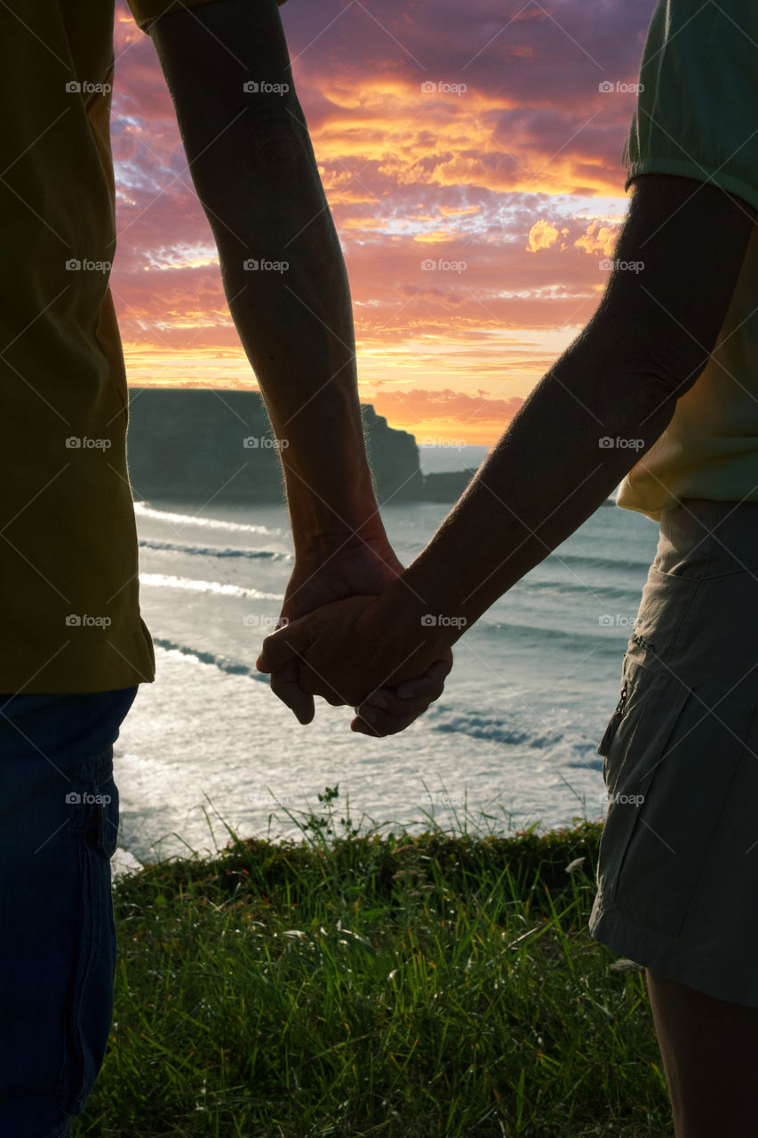 Couple holding hands at sunset