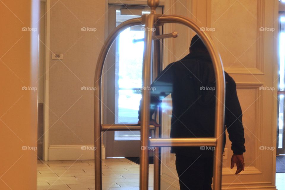 A hotel bellhop pulling the luggage rack outside to assist the next client with getting their luggage to their room!