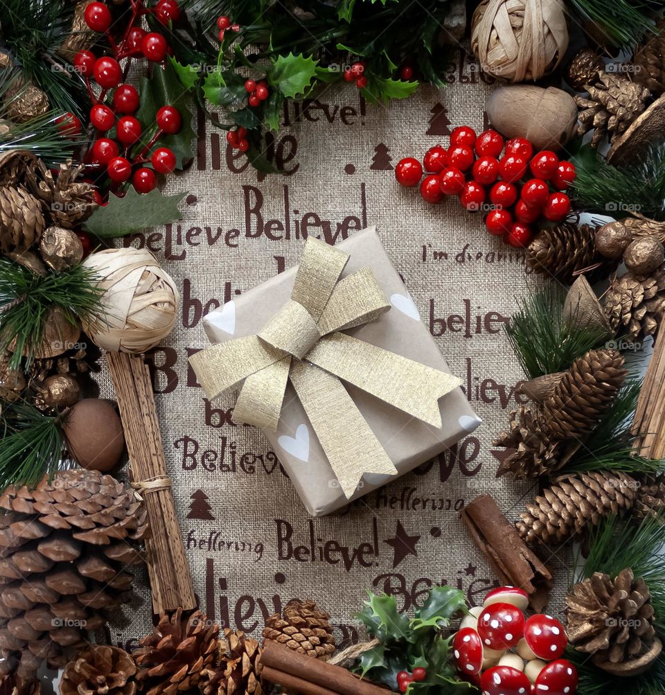 Festive flat lay of decorations centred around a wrapped present with the word “believe”