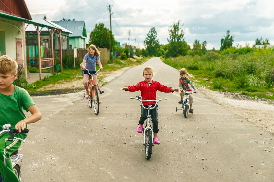 Kids are playing outside in the village, riding bicycles