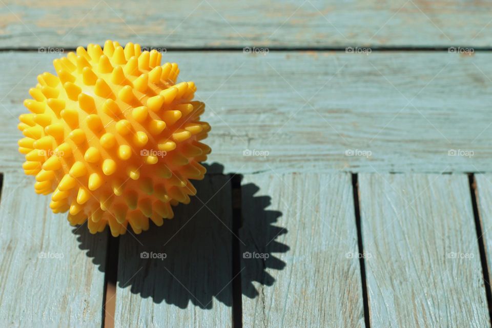 Yellow exercise ball with spikes on blue table