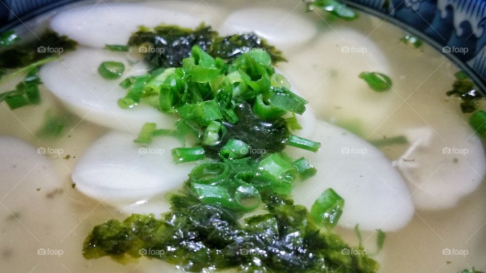 Korean rice cake soup. Also known as Tteokguk or Ddeokguk. Topped with some sliced scallions or shallots and dried seaweed. A delicious meal.