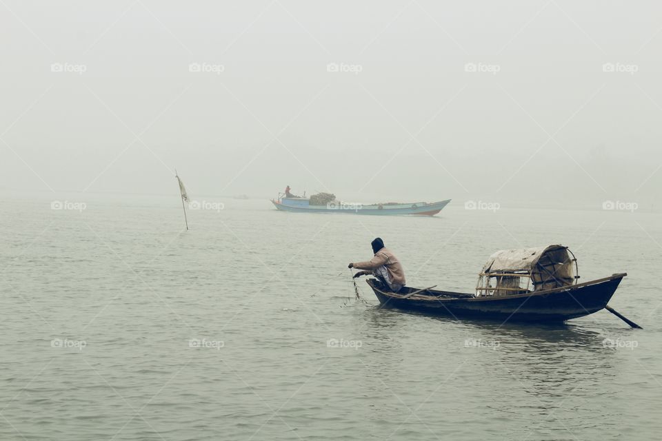 A decent view of a winter morning . A Fisherman try to collect some Fishes during the winter season . 
