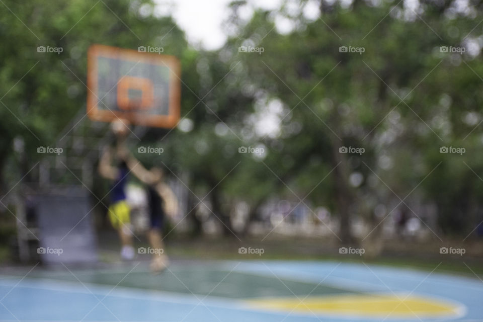 Blurry image teens playing basketball in the morning at BangYai Park , Nonthaburi in Thailand.