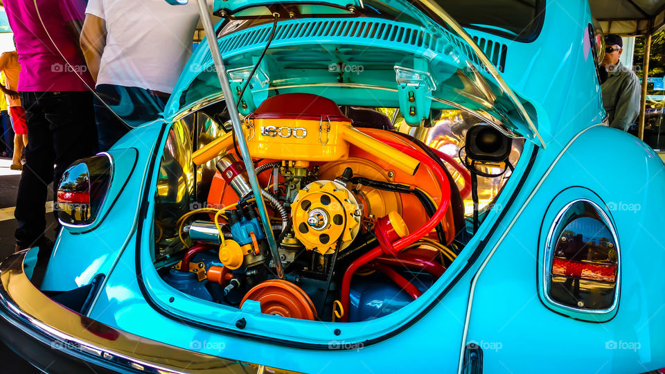 Motor, parte traseira de um Fusca azul claro tuning. Cores nitidas vibrantes, laranja, amarelo e vermelho relevantes em destaque.