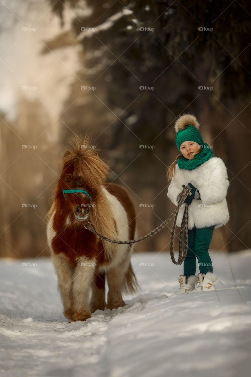 Little girl with pony at early spring day
