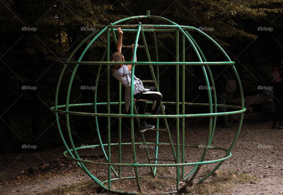 A boy climbing in the metal planet globe at the playground, Bulgaria.