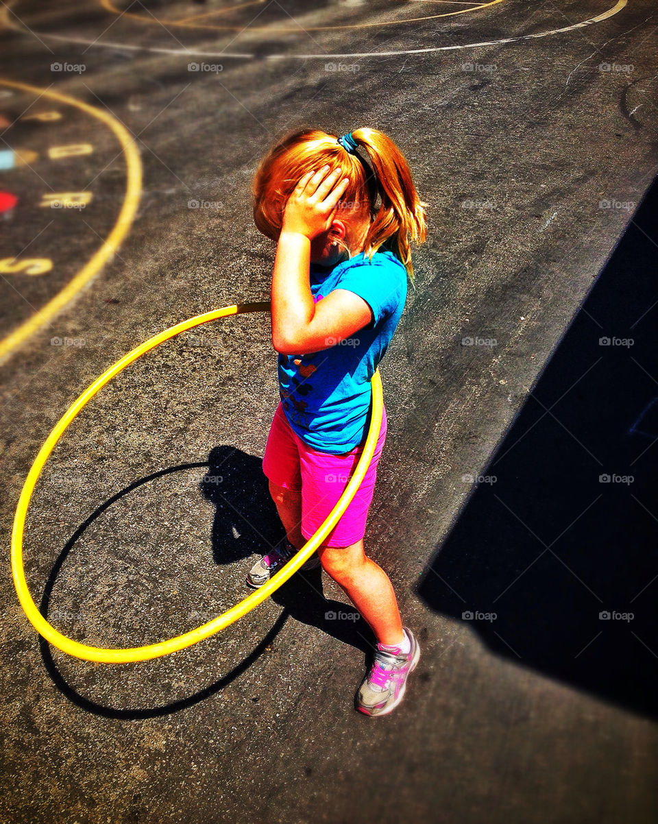 Young girl spinning a hula hoop on a playground