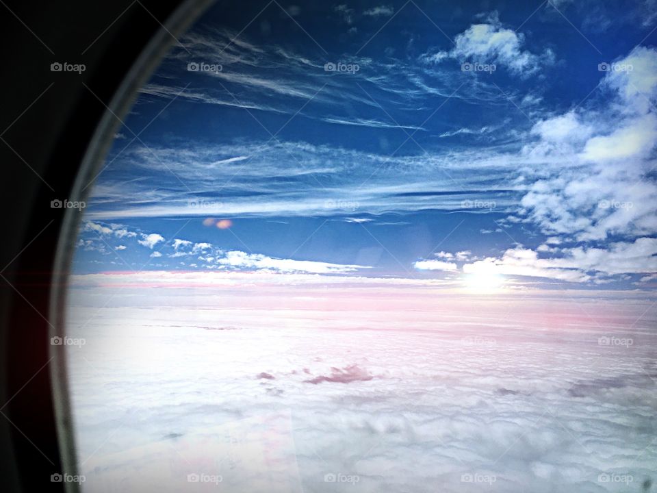 View from a jet plane. Aerial view of clouds and sun as seen through an airline window.