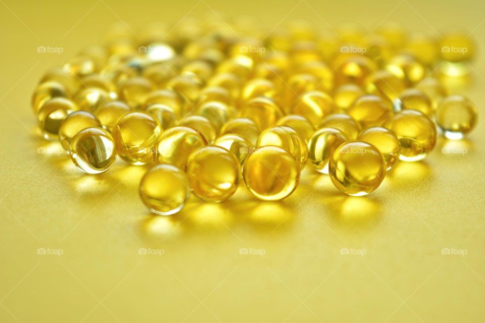 round vitamins capsules oils beautiful texture close up yellow background, healthy