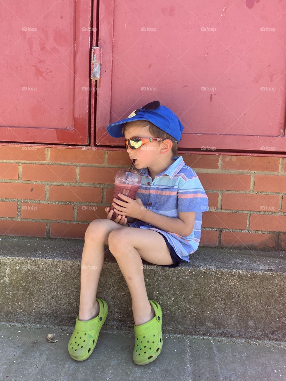 Boy drinking a berries smoothie 