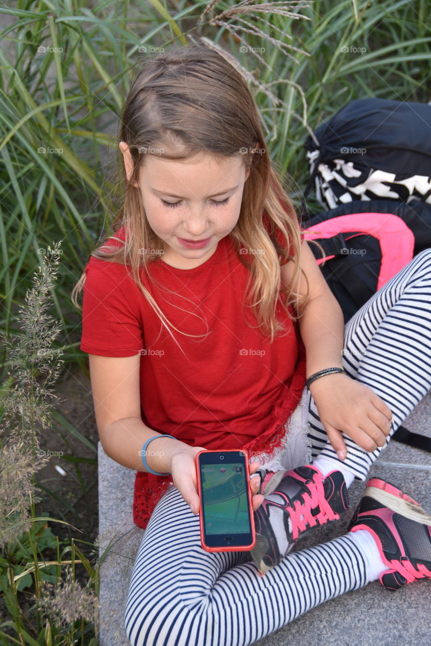 Little girl playing game on mobile phone