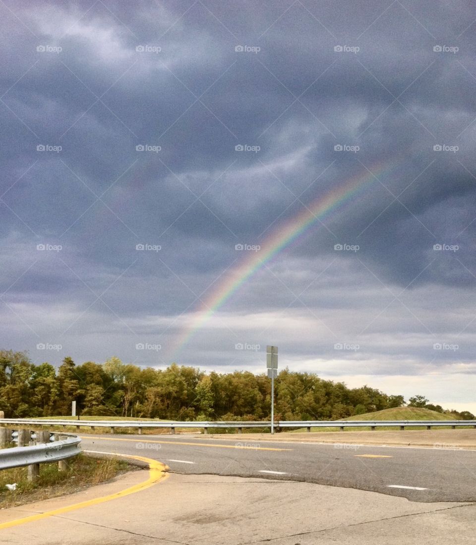 Road by exit ramp with a rainbow