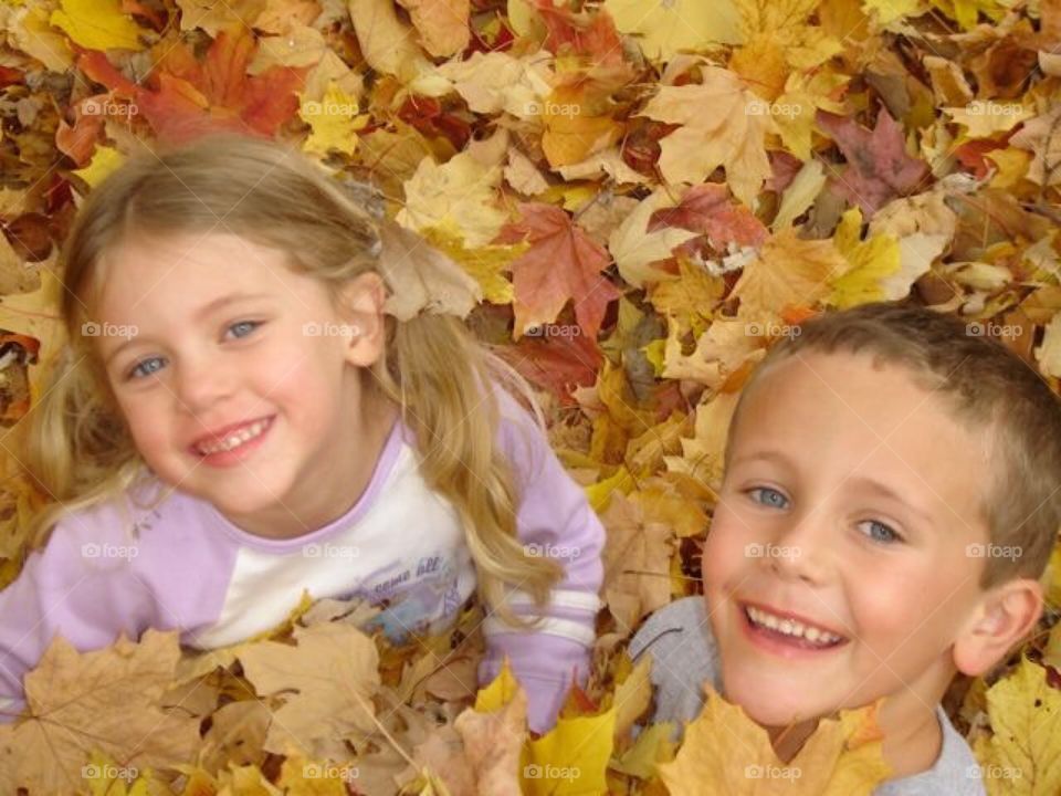 Fall- playing in a pile of leaves .