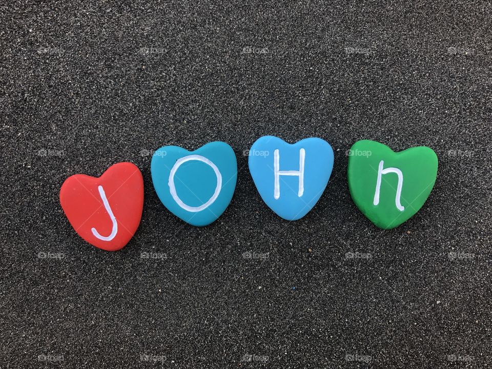 John, masculine name with colored heart stones over black volcanic sand