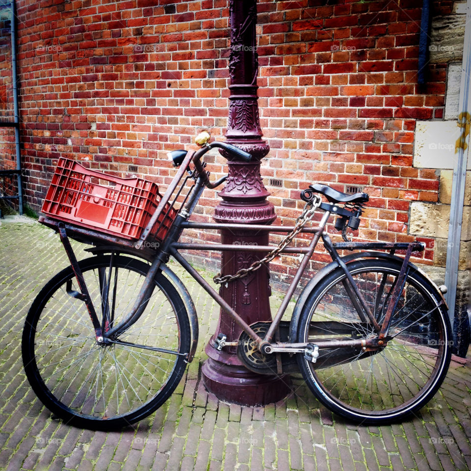 A vintage bicycle parked against a street lamp