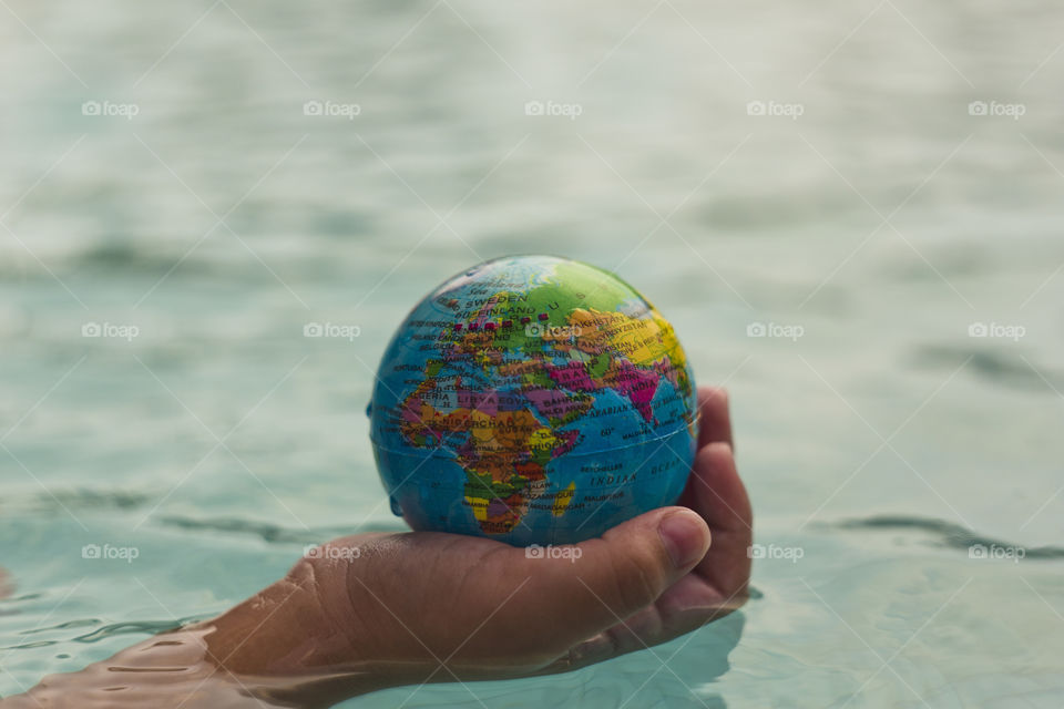 hand holding world sphere, showing Africa, Europe and Asia continents