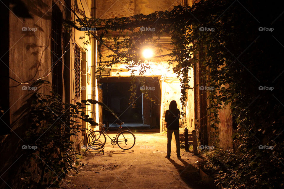 silhouette of a sad lone man in a dark courtyard