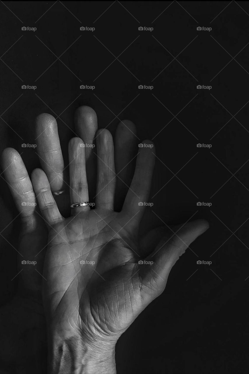 Close-up in black and white of two old hands of a man and a woman with wedding rings