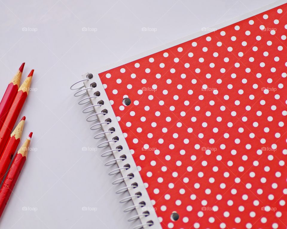 Red color of color pencil and book on white background.