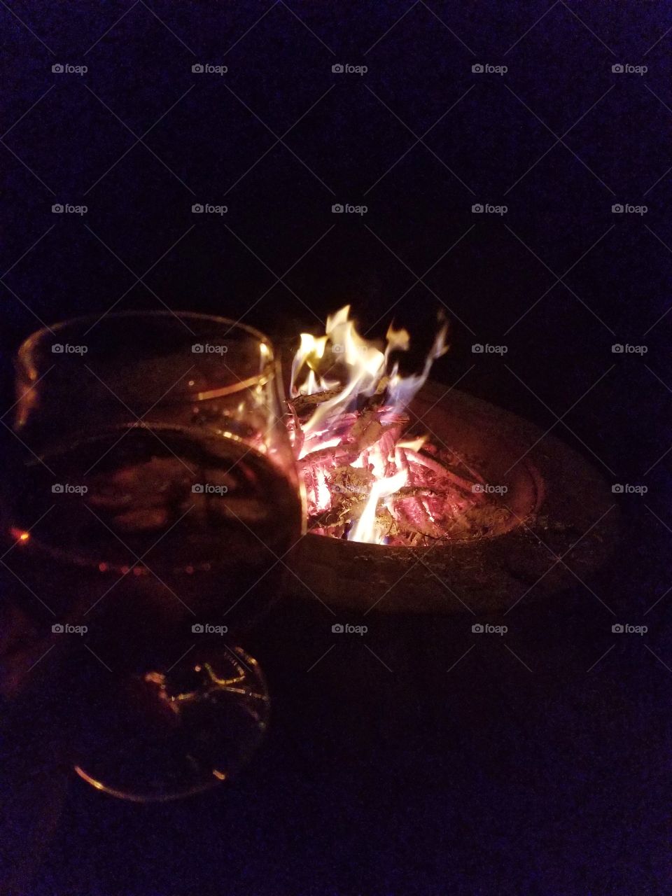 Colorful dancing flames of fire pit nights of the country light, whiskey glass sipping.