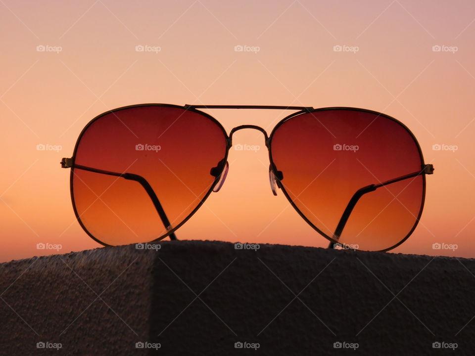 Sunglasses with sunset light background on wall