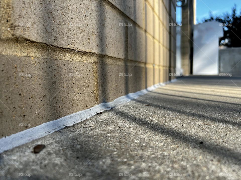 Low angle view of brick wall meeting concrete landing. Angular shadows contrast with the granite.