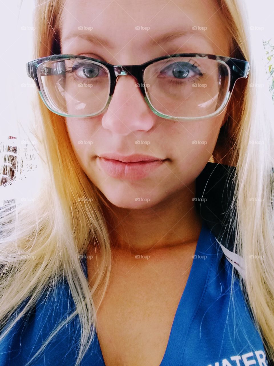 young woman with blond hair wearing glasses taking a selfie